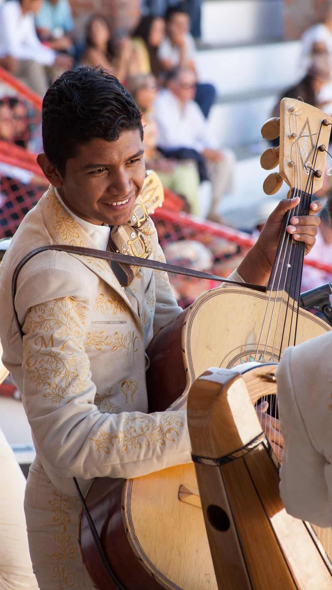 Vibrante celebración de San Miguel de Allende con músico tocando la guitarra y multitud animada.