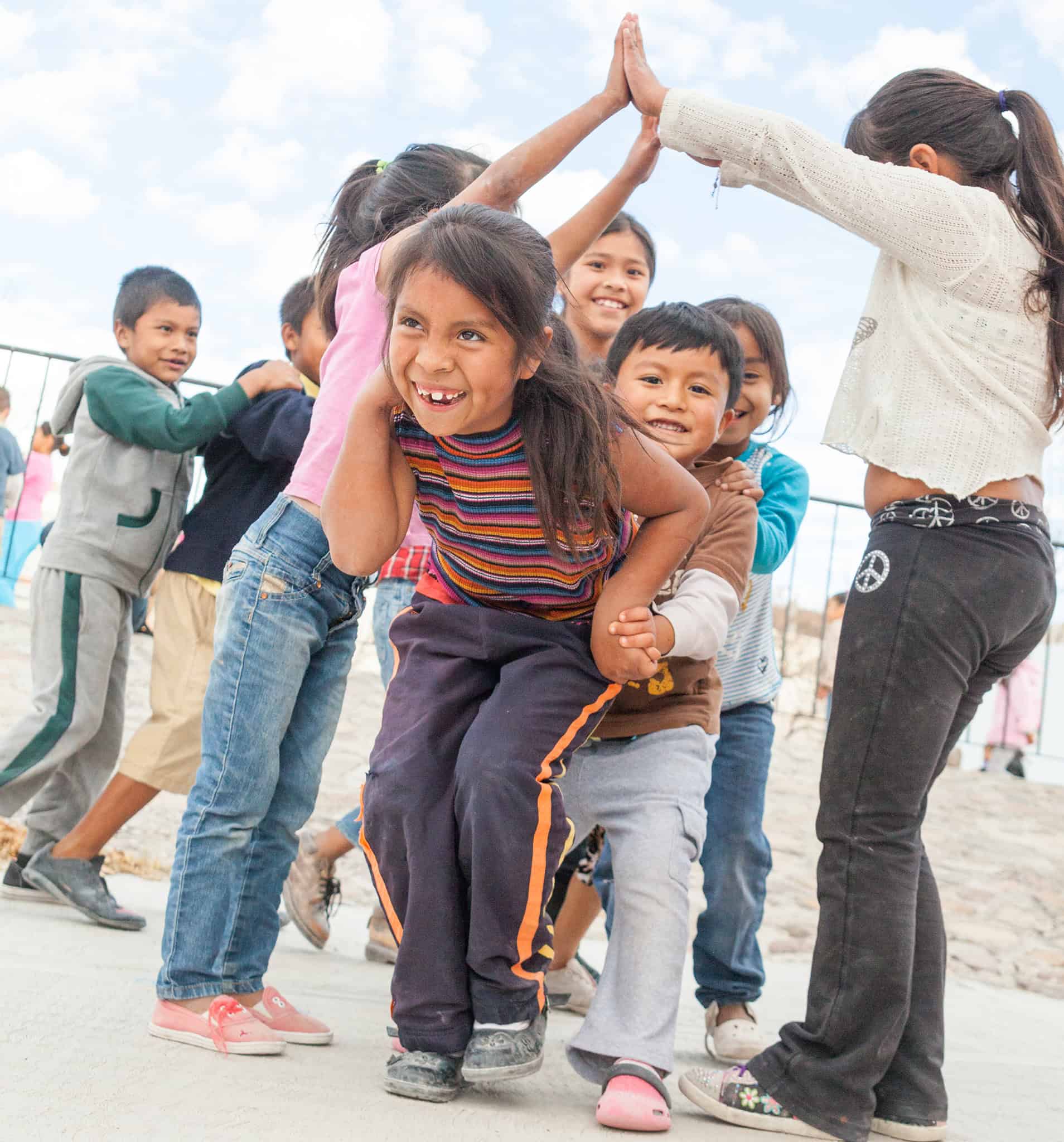 Niños alegres jugando y sonriendo al aire libre en un evento comunitario de San Miguel.