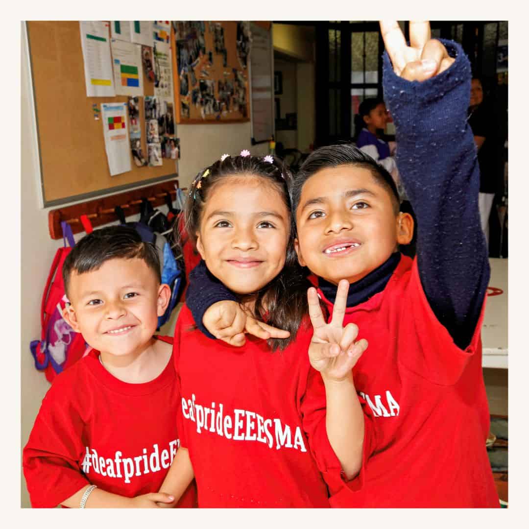 Niños felices vistiendo, sonriendo y haciendo señales de paz en el interior, mostrando el impacto de una organización miembro de la red sin fines de lucro de SMCF.