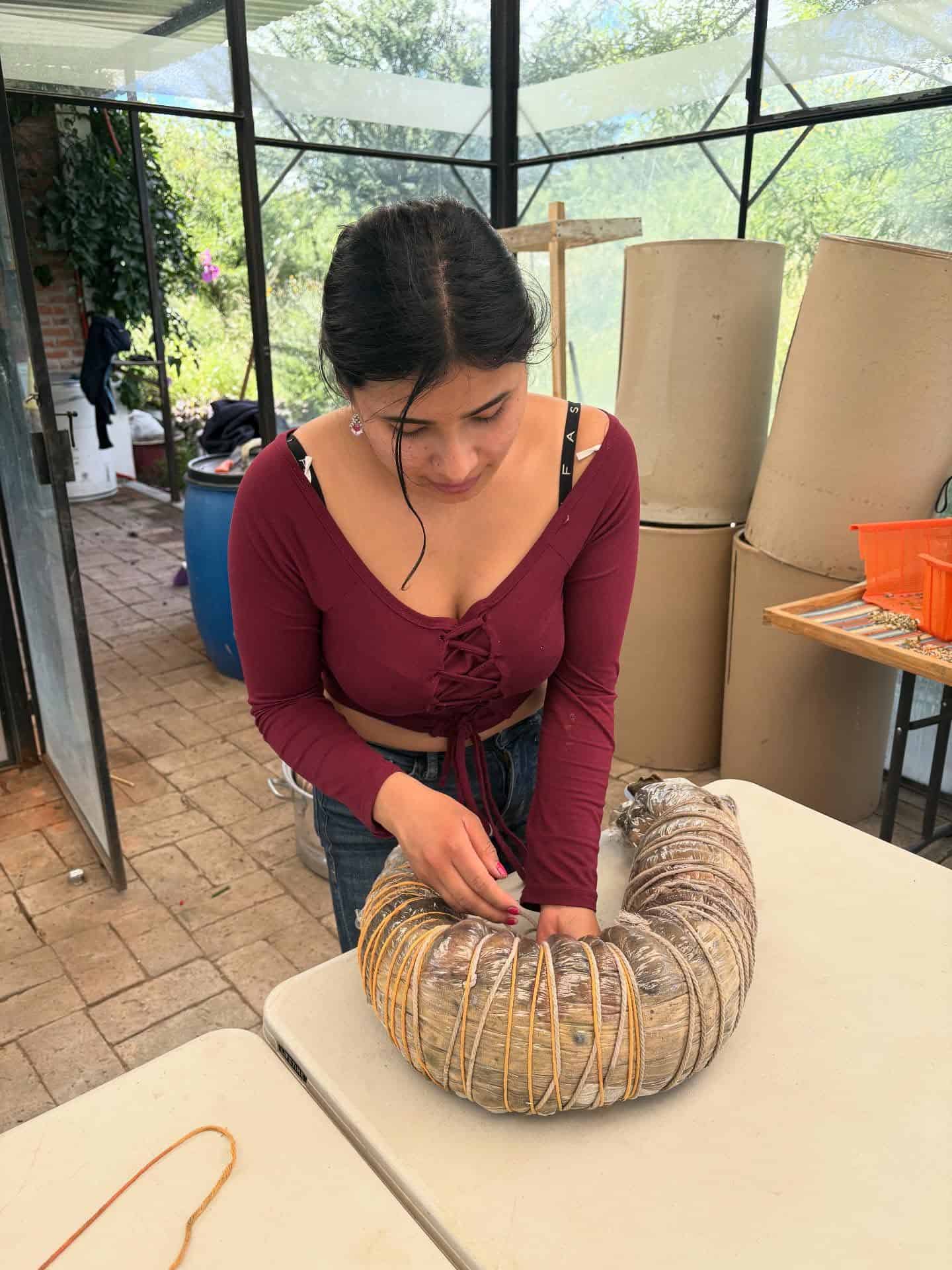 Mujer creando una pieza de arte tejida con materiales naturales en el evento SMCF.