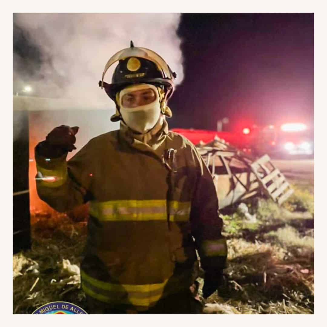 Bombero con equipo de protección, casco y máscara en escena nocturna.