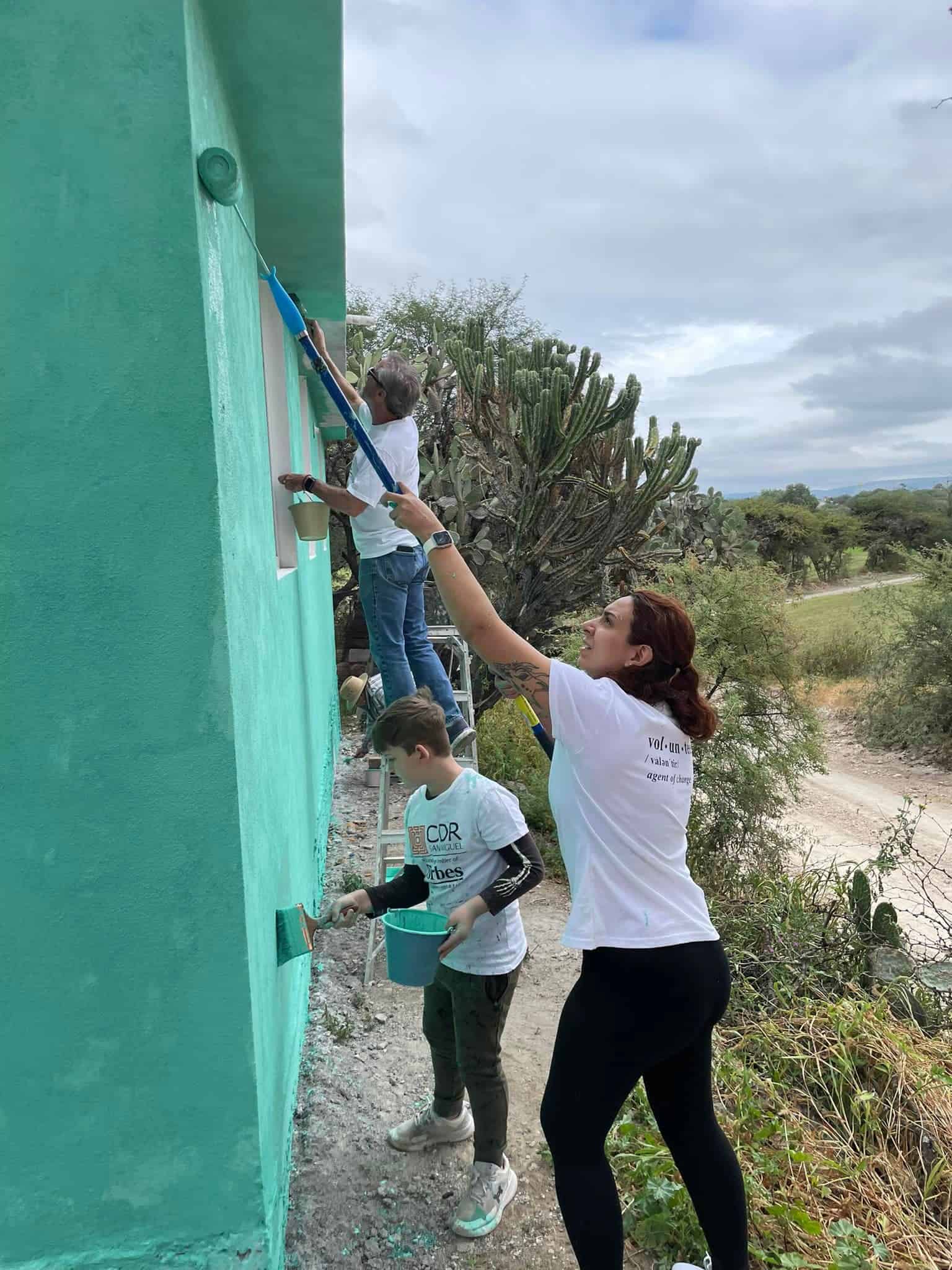 Colorful house painting volunteers painting exterior walls for community improvement and social responsibility in San Miguel.