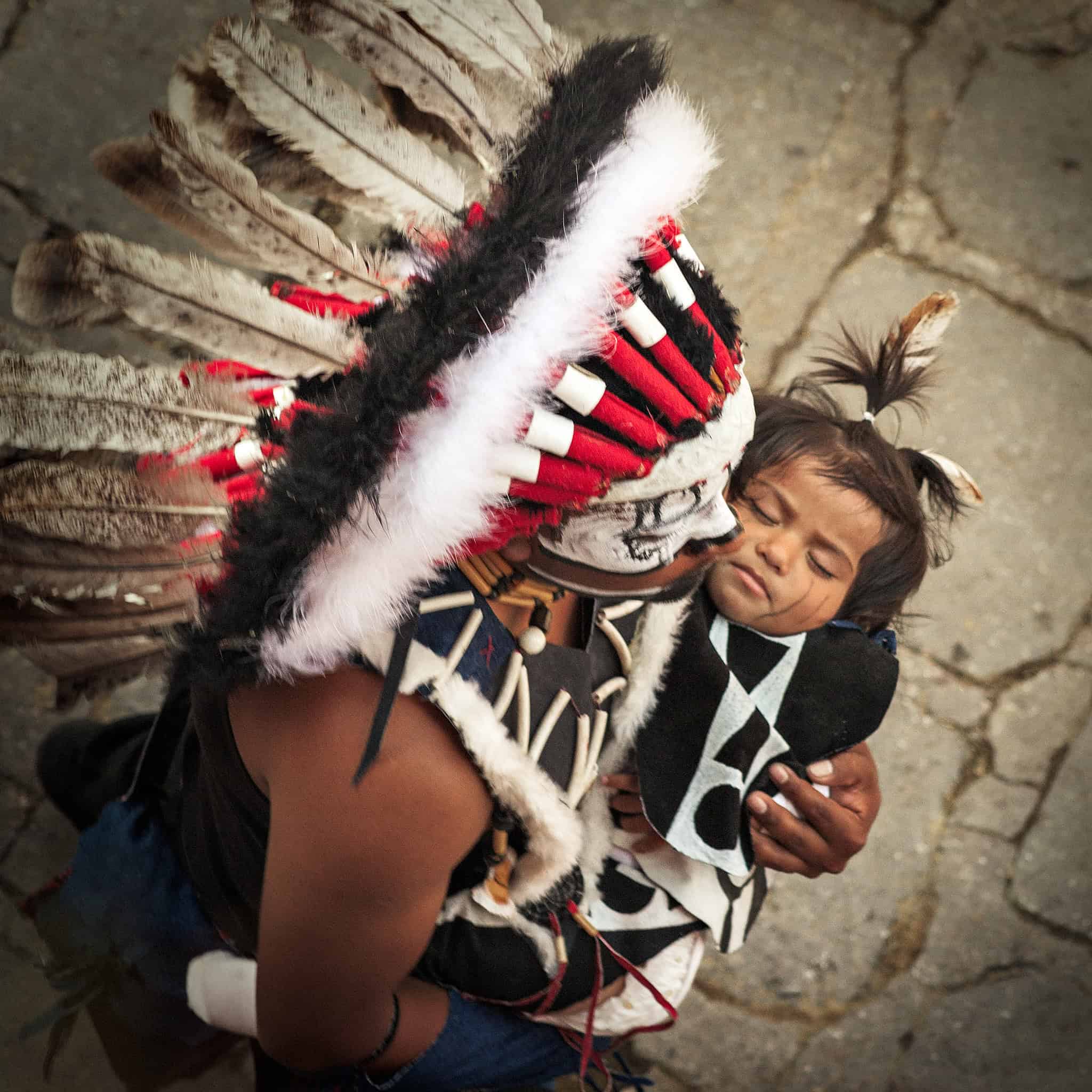Traditional indigenous girl wearing tribal attire and feather headdress in San Miguel, Mexico.