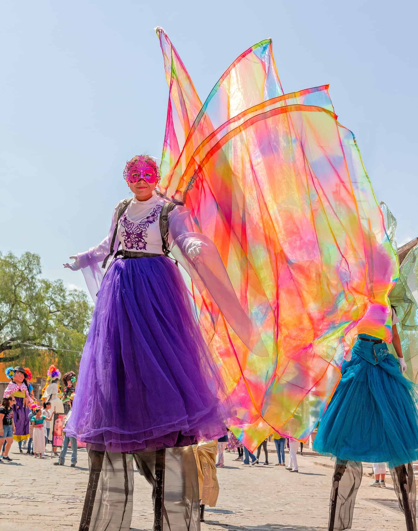 Colorful butterfly stilt performers at a festive San Miguel event for vibrant celebration and cultural entertainment.
