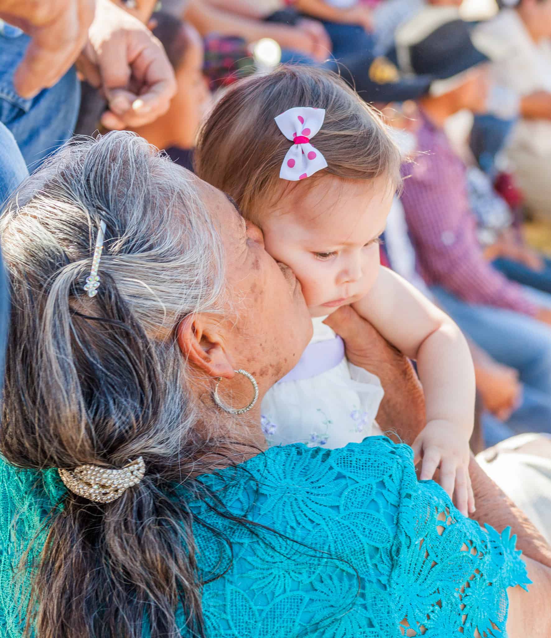 Grandmother hugging a young girl at a San Miguel community event, showcasing family love and connection.