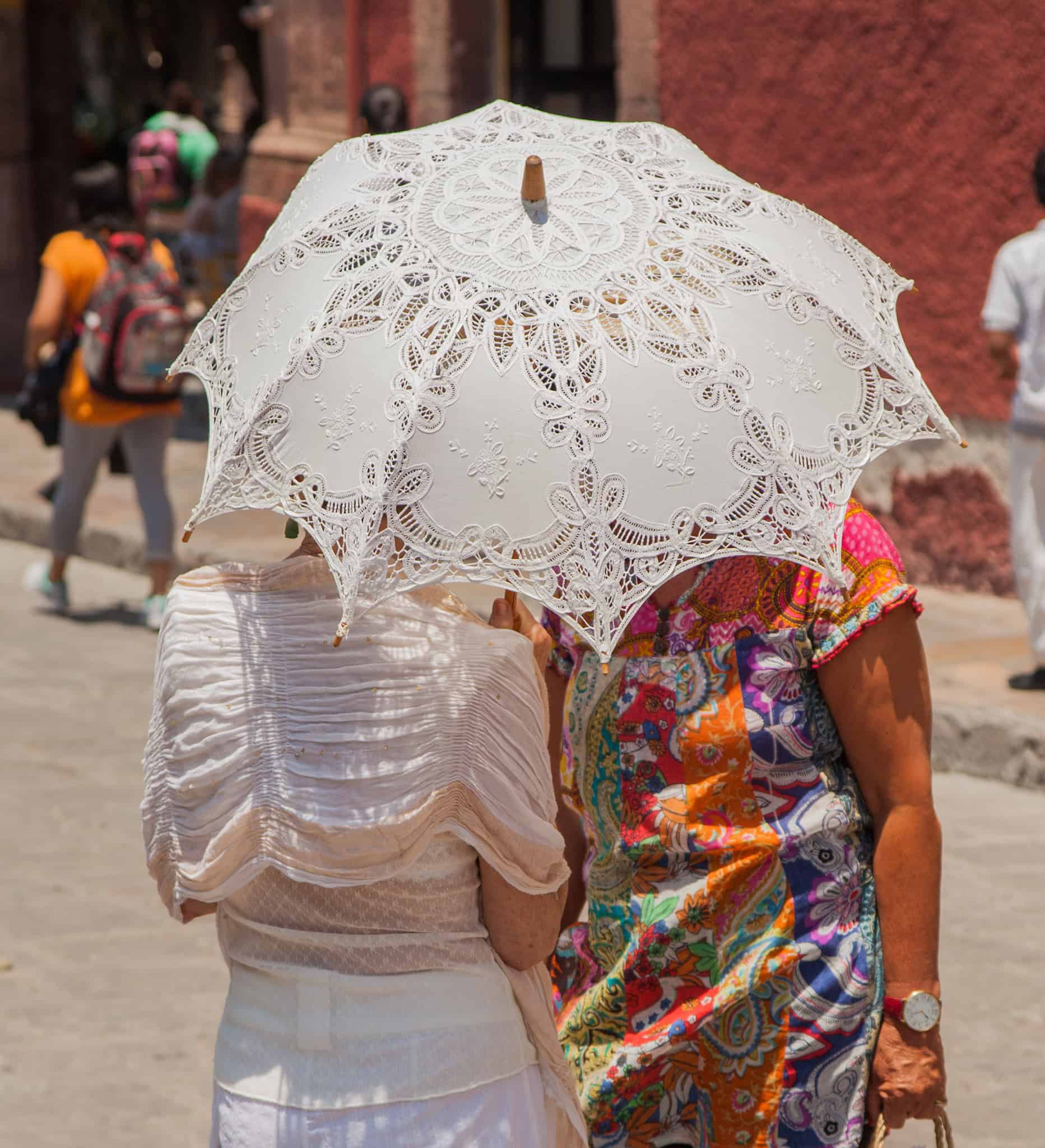 Colorful traditional Mexican attire with umbrellas on a lively San Miguel street scene.