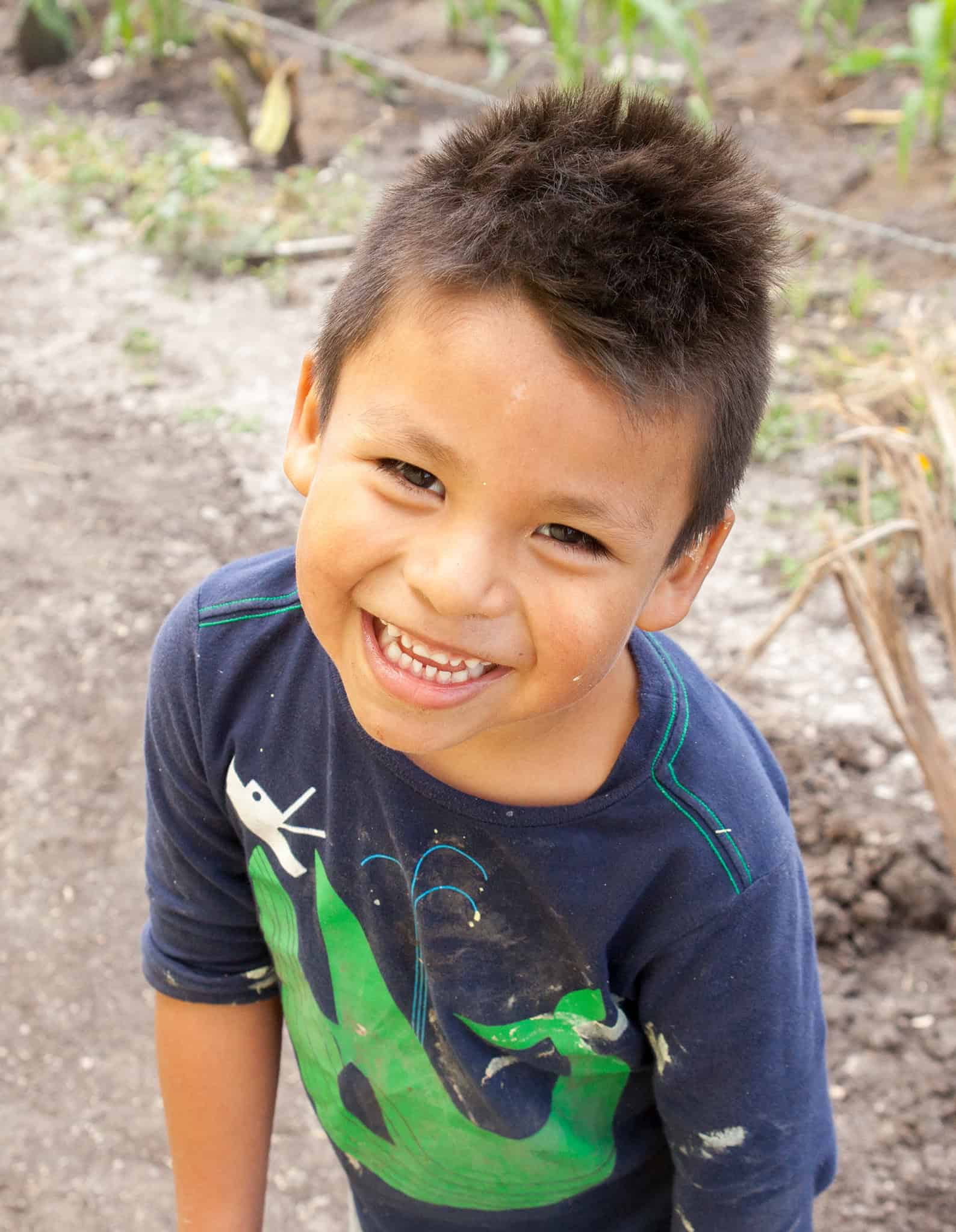 Smiling young boy outdoors in casual clothing on San Miguel farm land.