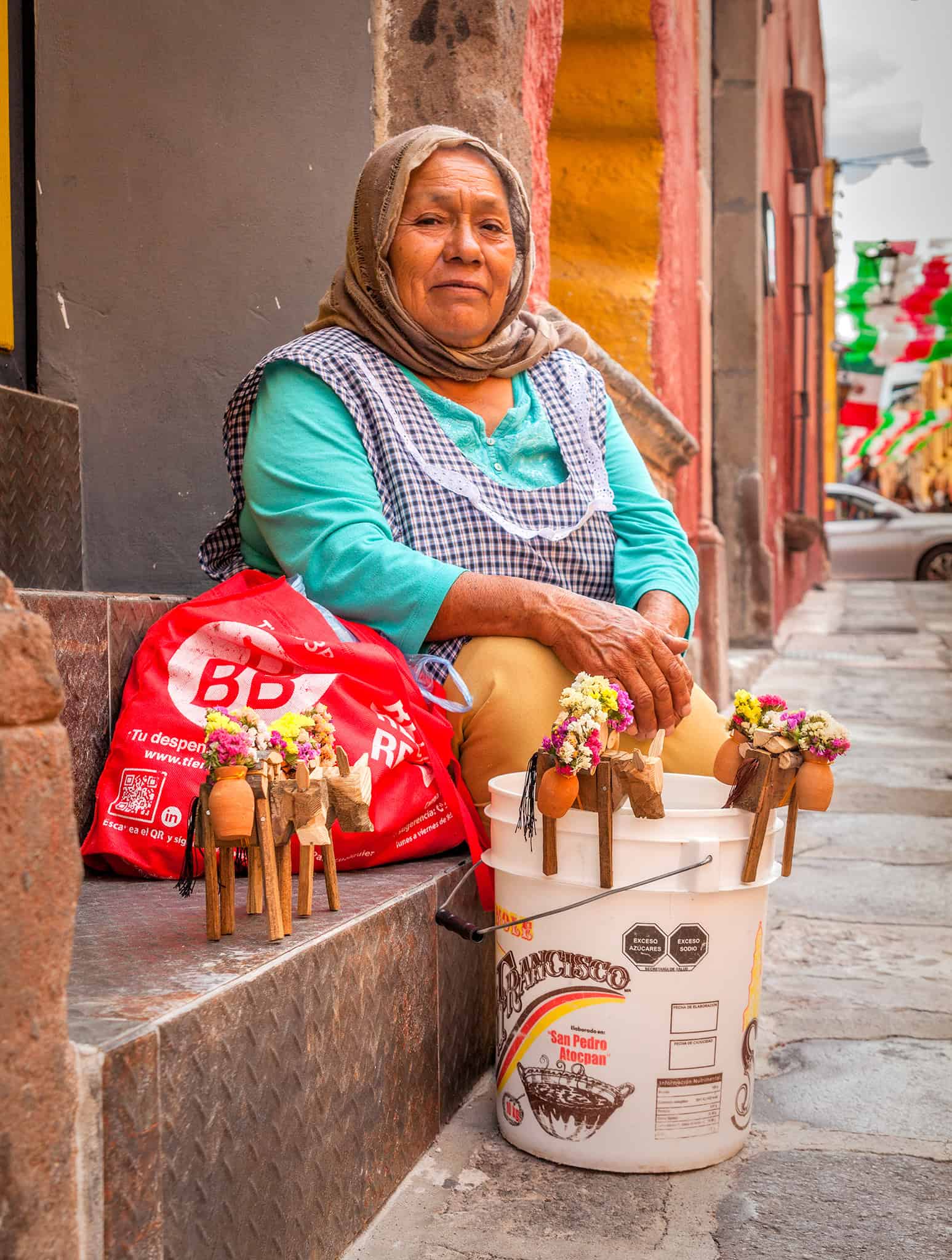 Vendedora callejera en San Miguel de Allende vendiendo artesanías y flores tradicionales en la calle.