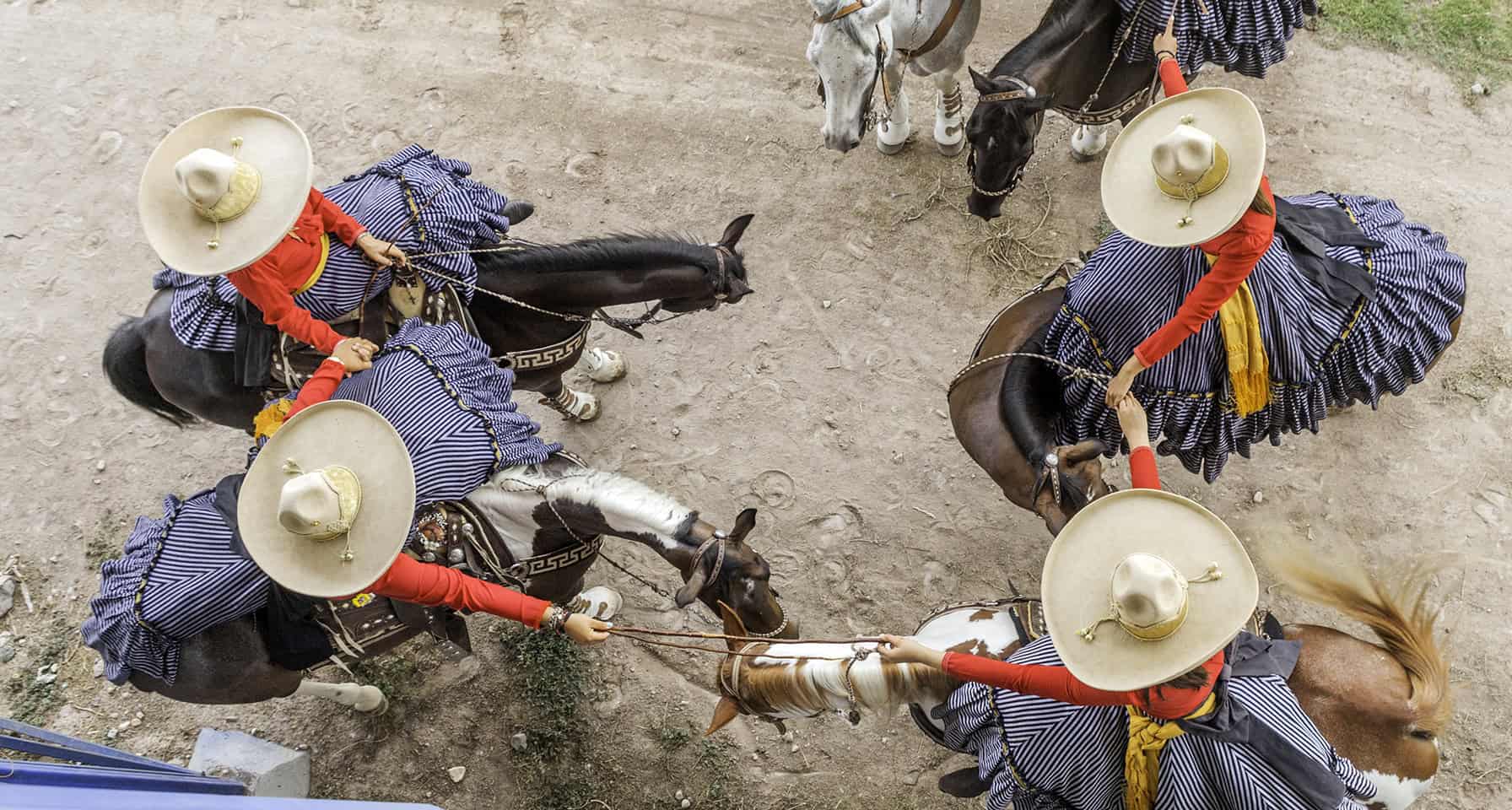 Colorful traditional Mexican dancers performing on horseback during a cultural festival in San Miguel.