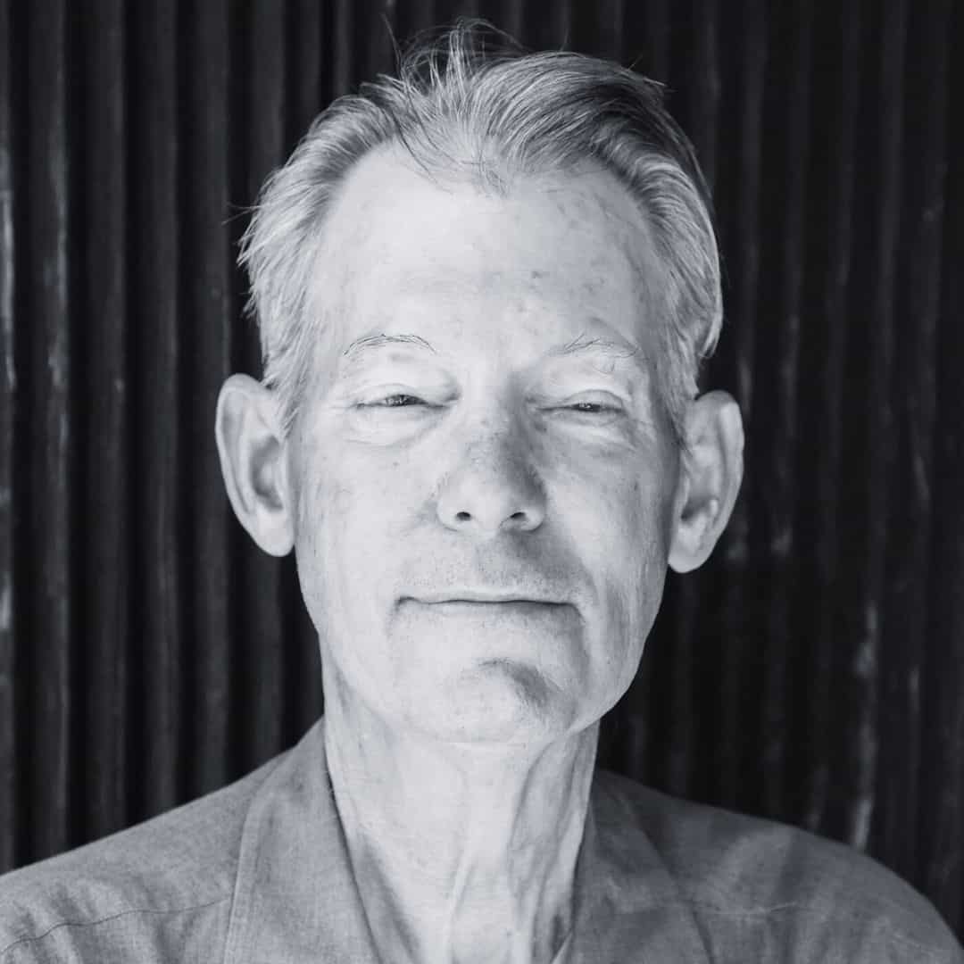 Stylish man wearing a cap and sunglasses, outdoor setting, black and white photo.