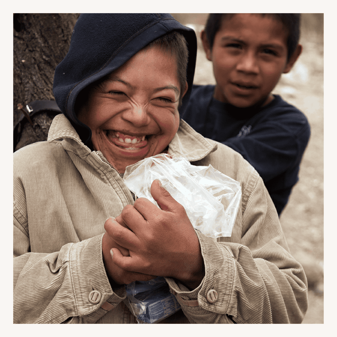 Joyful boy smiling outdoors holding a plastic bag, featuring a SMCF Nonprofit Network Member organization.