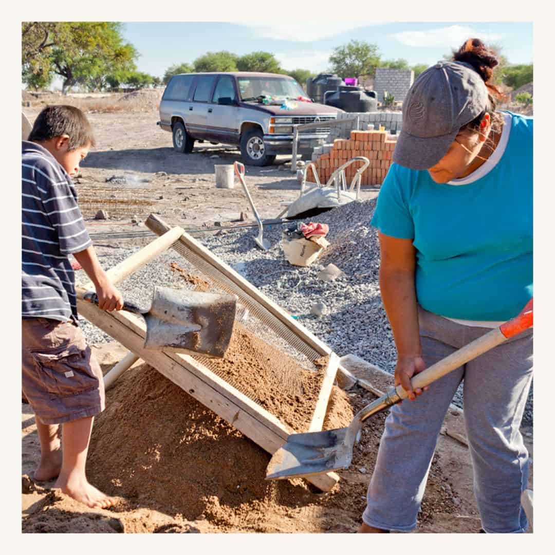 Volunteers working together on a construction site, shoveling dirt and mixing concrete, featuring a SMCF Nonprofit Network Member organization.