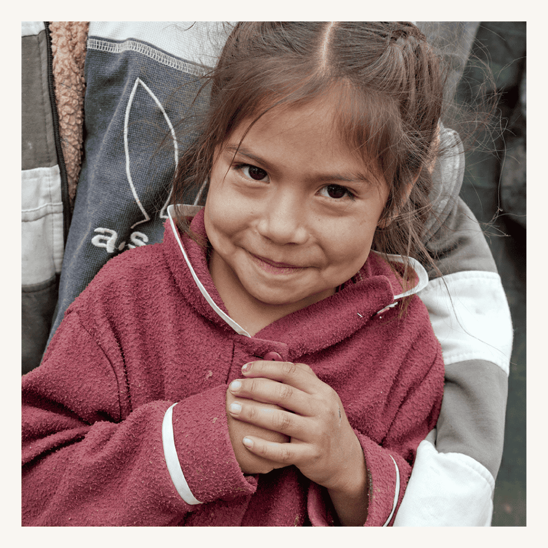 Child smiling with clasped hands, participating in a community or charity event in Mexico, featuring a SMCF Nonprofit Network Member organization.